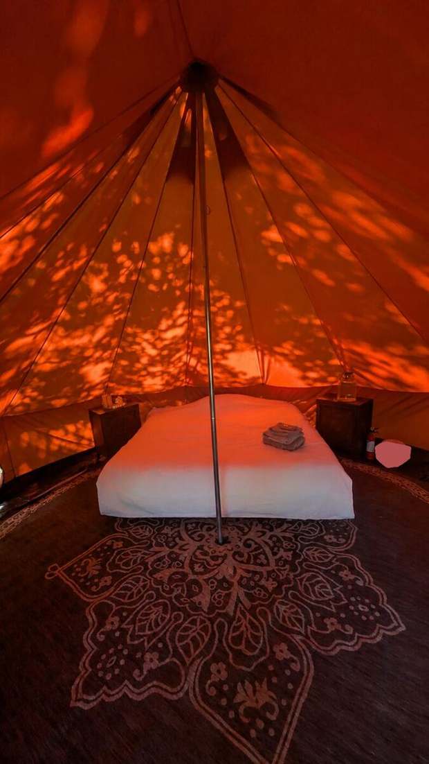 Inside a canvas bell tent with a made bed and rug