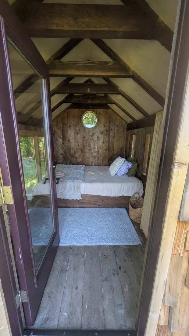 Inside the wooden hut, bed made and ready