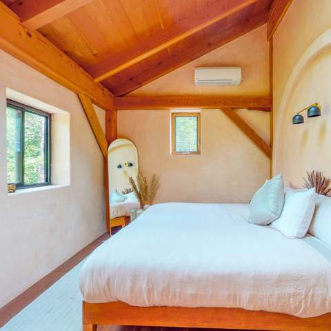 Plaster room with a king bed and forest window