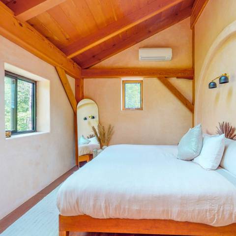 Plaster room with a king bed and forest window